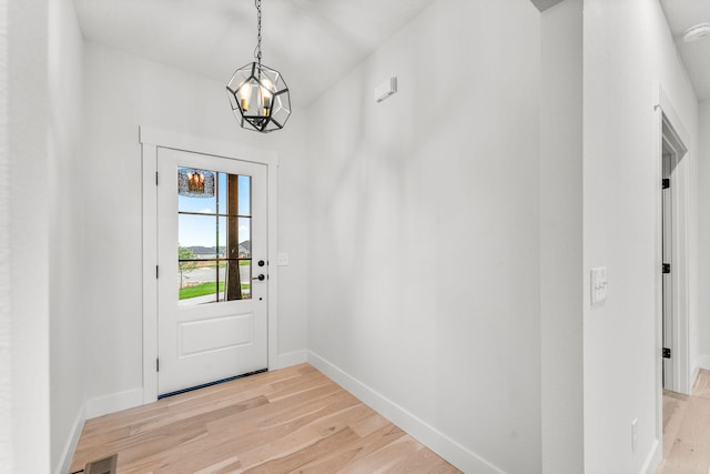 doorway to outside with an inviting chandelier and light hardwood / wood-style floors