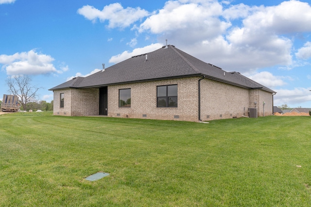 rear view of property featuring central AC unit and a lawn