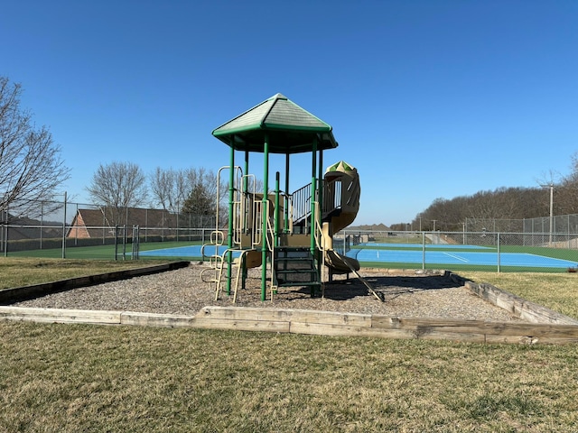 view of playground with a water view, tennis court, and a lawn