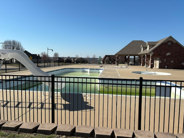 view of pool with a water slide and a patio area