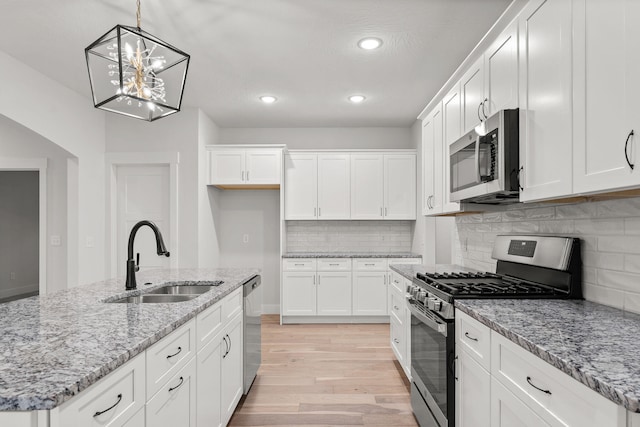 kitchen featuring a kitchen island with sink, appliances with stainless steel finishes, sink, and white cabinetry