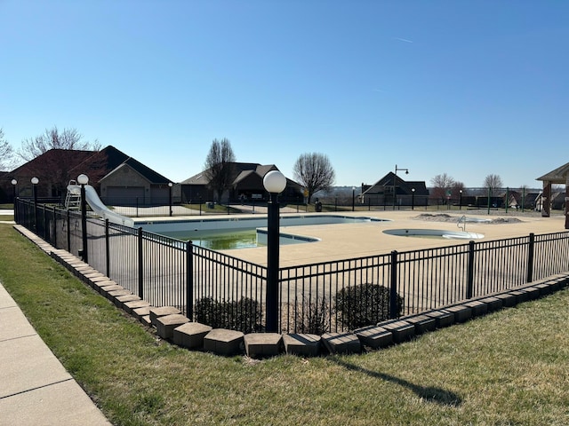 view of pool with a water slide and a lawn