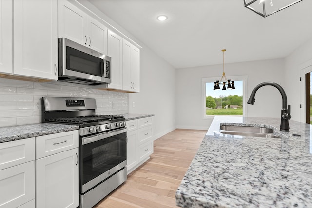 kitchen with stainless steel appliances, sink, and white cabinetry