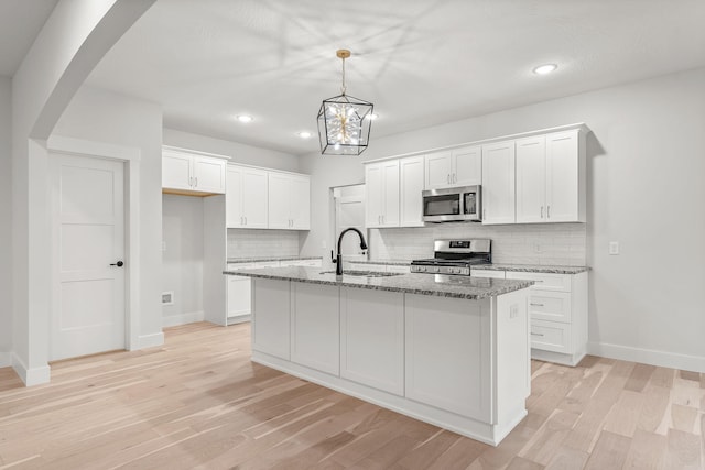 kitchen featuring appliances with stainless steel finishes, white cabinetry, a kitchen island with sink, and sink