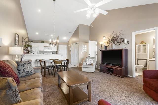 living room with ceiling fan with notable chandelier, high vaulted ceiling, and light colored carpet