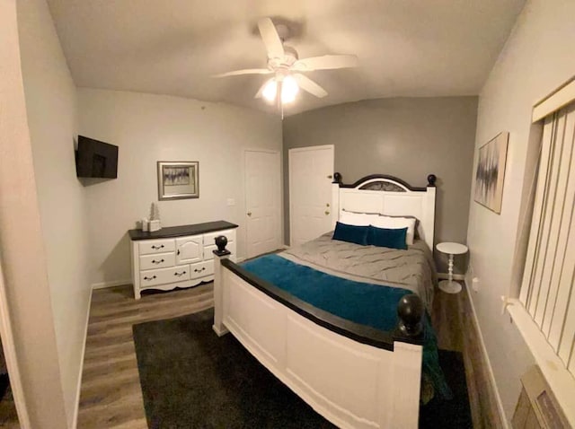 bedroom with ceiling fan, vaulted ceiling, and dark hardwood / wood-style flooring