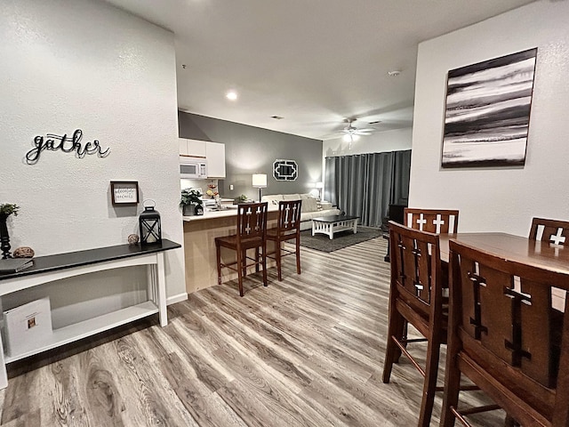 dining space with light hardwood / wood-style floors and ceiling fan