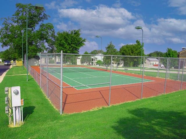 view of tennis court featuring a lawn