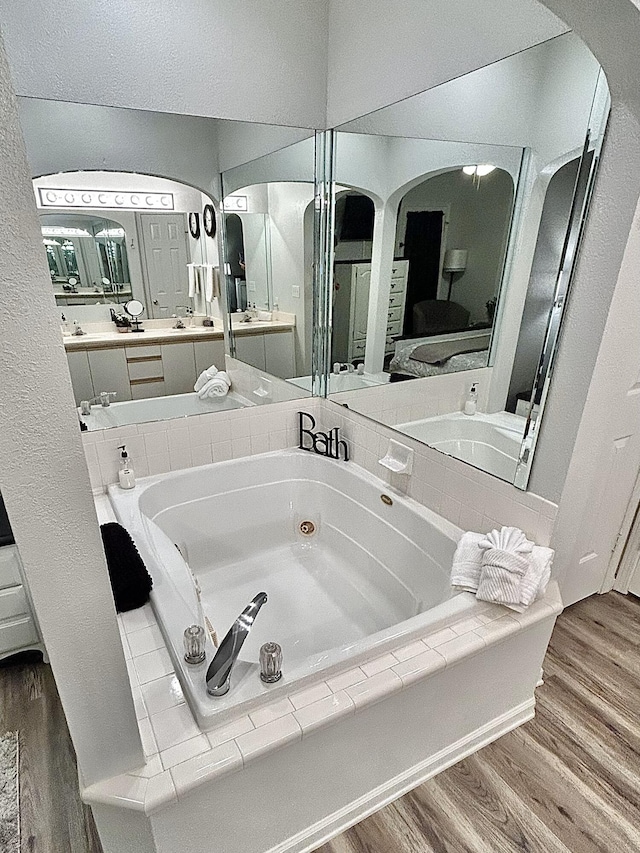 bathroom with wood-type flooring, vanity, and a bath