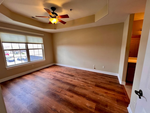 spare room with a tray ceiling, hardwood / wood-style floors, and ceiling fan