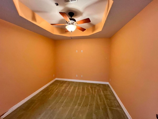 unfurnished room featuring a tray ceiling, carpet, and ceiling fan