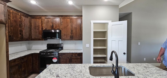 kitchen with gas stove, light stone countertops, sink, tasteful backsplash, and wood-type flooring