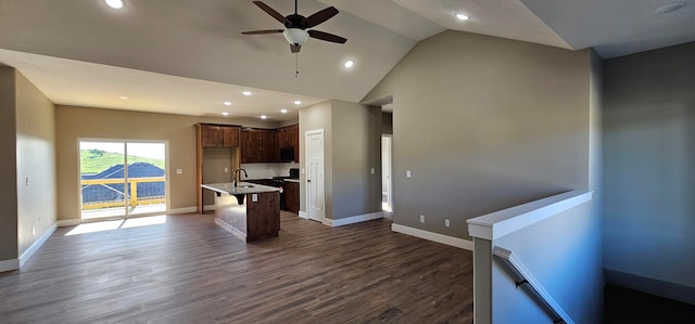 kitchen featuring a center island with sink, sink, ceiling fan, dark hardwood / wood-style flooring, and a breakfast bar area