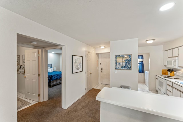 kitchen featuring light carpet, white appliances, white cabinetry, and washer / clothes dryer