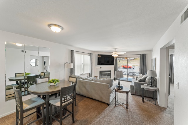 carpeted living room featuring ceiling fan and a textured ceiling