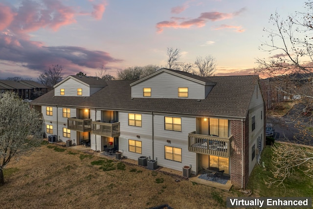 back house at dusk featuring a balcony and central air condition unit