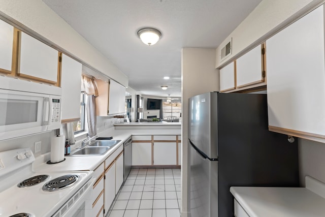 kitchen with light tile patterned floors, appliances with stainless steel finishes, sink, and white cabinetry