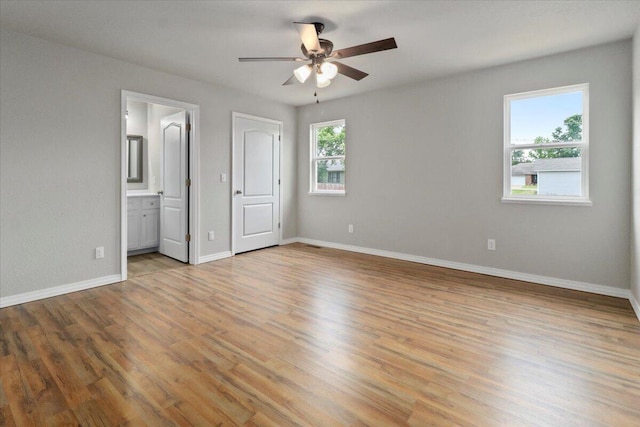 unfurnished bedroom featuring ensuite bathroom, ceiling fan, and light wood-type flooring