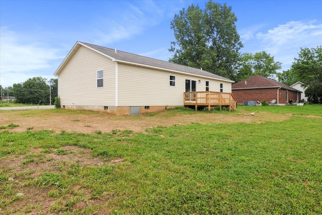 rear view of property featuring a wooden deck and a lawn