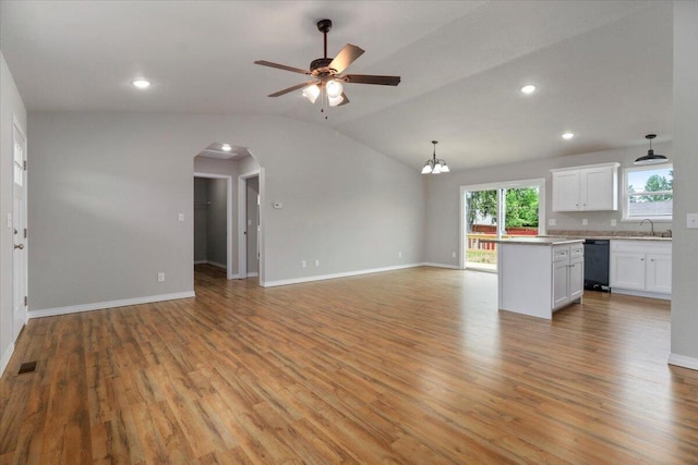 unfurnished living room with lofted ceiling, ceiling fan with notable chandelier, sink, and light wood-type flooring