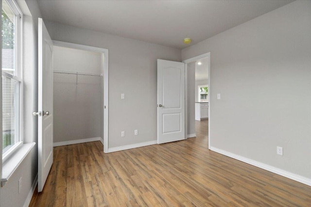 unfurnished bedroom with a closet, light hardwood / wood-style floors, and multiple windows