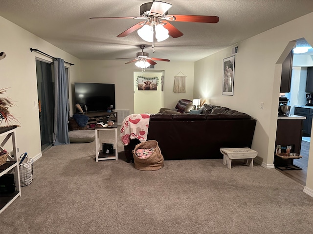 carpeted living room featuring ceiling fan and a textured ceiling