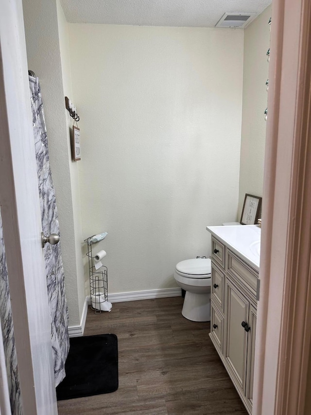 bathroom featuring hardwood / wood-style floors, toilet, vanity, and a textured ceiling