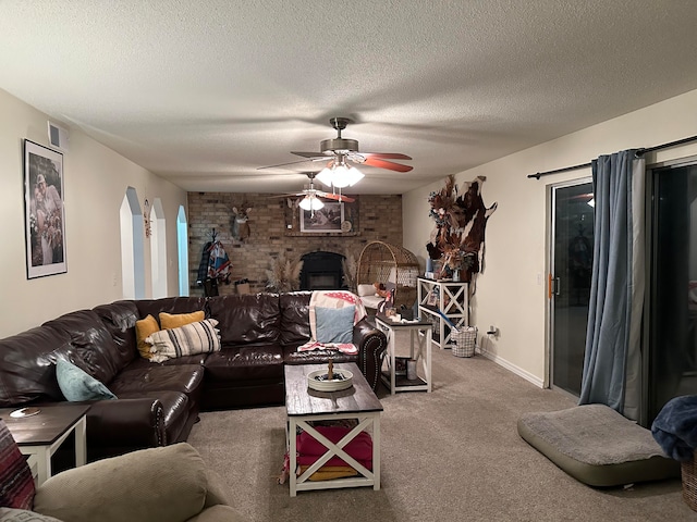 carpeted living room featuring ceiling fan, a textured ceiling, and a fireplace