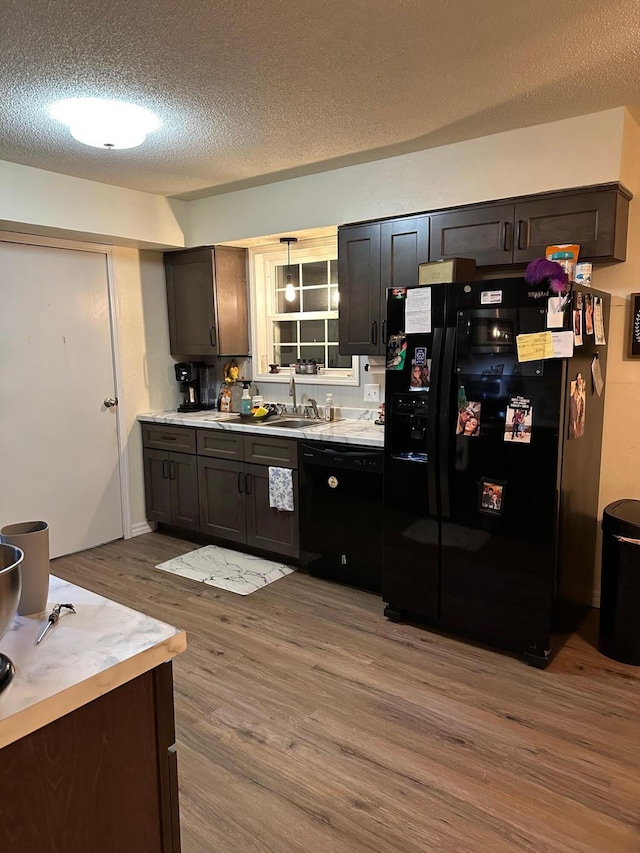 kitchen featuring dark brown cabinetry, light hardwood / wood-style flooring, and black appliances