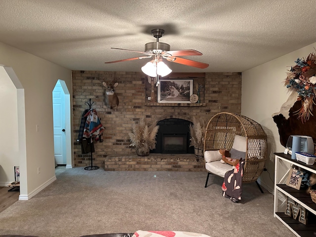 unfurnished living room with a brick fireplace, ceiling fan, carpet, and a textured ceiling