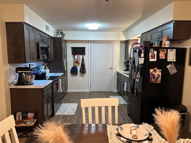 kitchen with dark brown cabinets, a textured ceiling, dark wood-type flooring, black refrigerator with ice dispenser, and range with electric stovetop