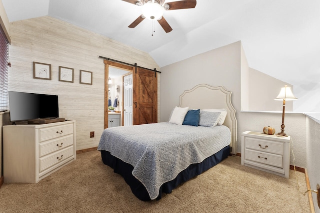 carpeted bedroom with ceiling fan, ensuite bathroom, a barn door, and vaulted ceiling