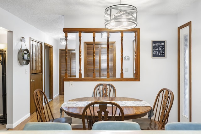 dining room with a textured ceiling, light hardwood / wood-style floors, and a notable chandelier