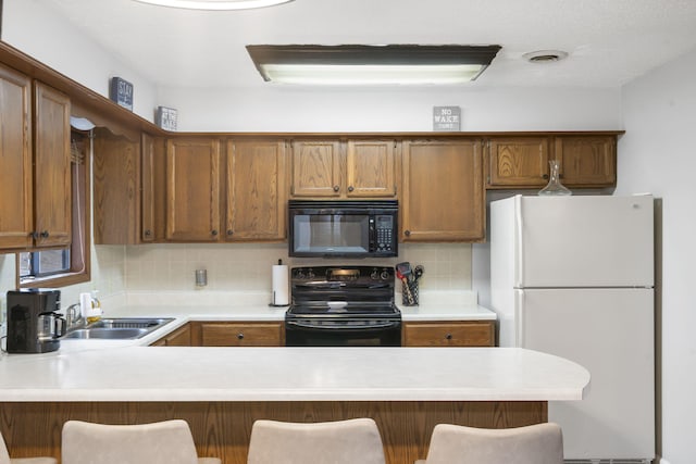 kitchen with backsplash, black appliances, and a breakfast bar