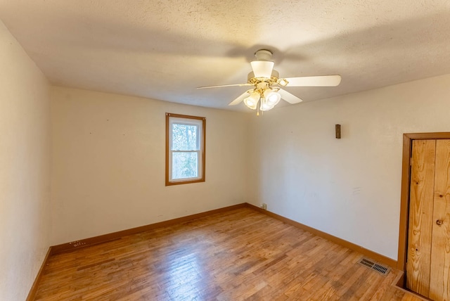 unfurnished room with ceiling fan, a textured ceiling, and light wood-type flooring