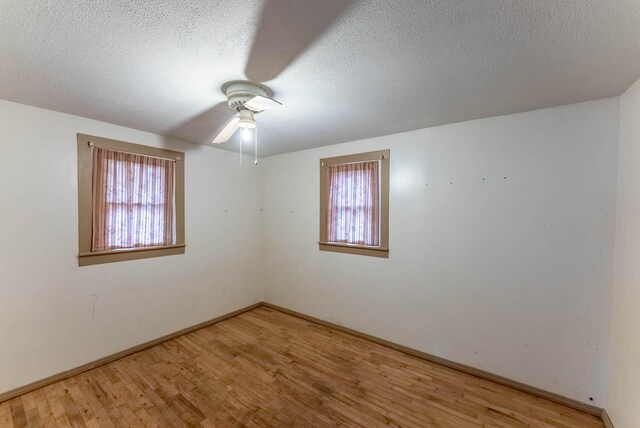 spare room featuring light wood-type flooring, a healthy amount of sunlight, ceiling fan, and a textured ceiling