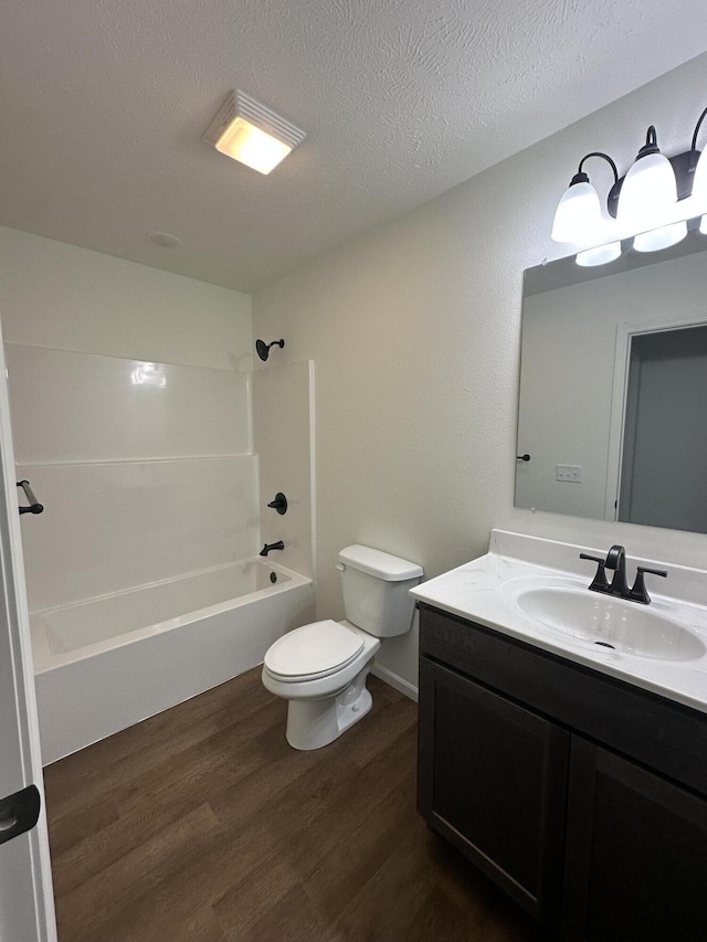 full bathroom featuring hardwood / wood-style floors, vanity, washtub / shower combination, toilet, and a textured ceiling