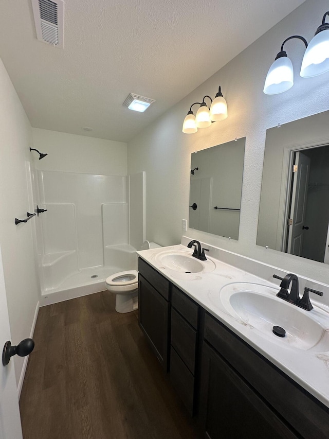 bathroom with vanity, toilet, a textured ceiling, walk in shower, and wood-type flooring