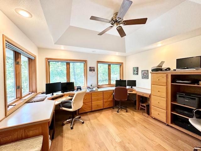 office area with a raised ceiling, light hardwood / wood-style flooring, a textured ceiling, and ceiling fan