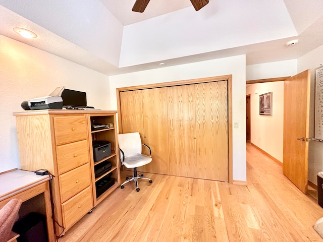 office featuring ceiling fan, light hardwood / wood-style floors, and a raised ceiling