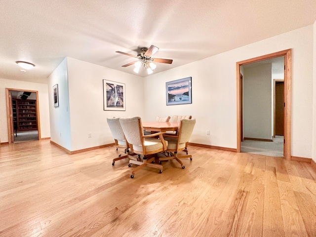 dining area with ceiling fan, light hardwood / wood-style floors, and a textured ceiling