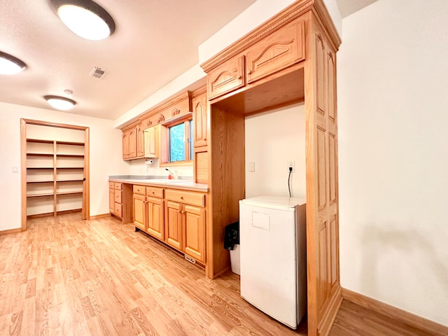 kitchen featuring light brown cabinetry, light hardwood / wood-style flooring, and refrigerator