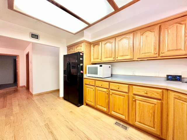 kitchen featuring light hardwood / wood-style floors and black fridge