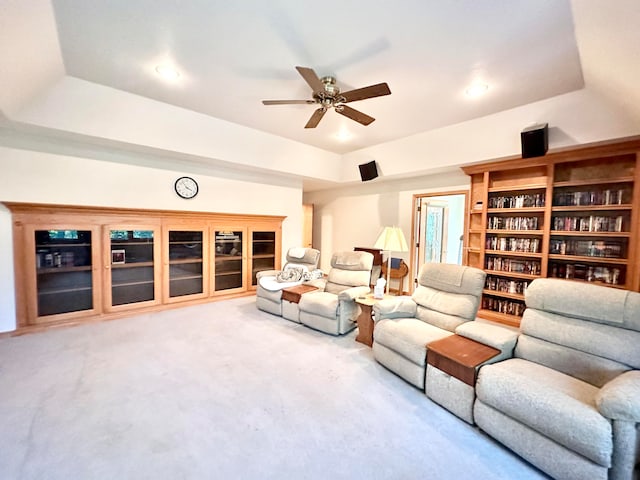 living room with ceiling fan, a raised ceiling, and carpet flooring