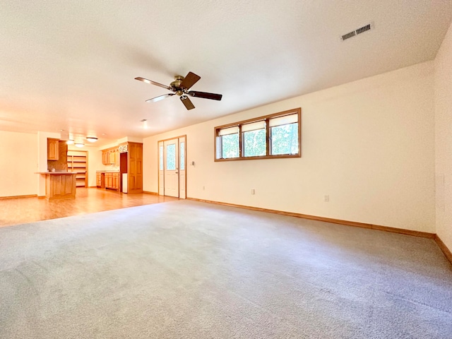 empty room with light hardwood / wood-style flooring, a textured ceiling, and ceiling fan