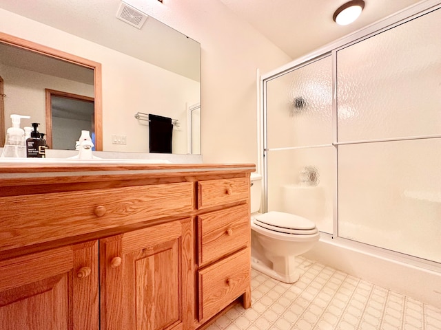 bathroom with vanity, toilet, and a shower with door