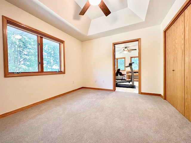 unfurnished bedroom featuring ceiling fan, a closet, carpet, and a raised ceiling