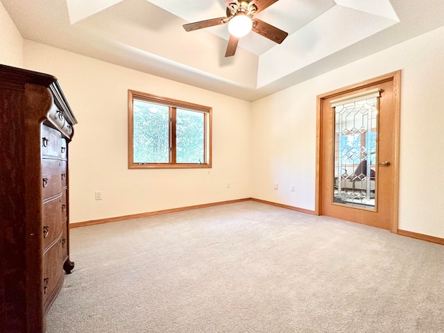 carpeted empty room with a raised ceiling and ceiling fan