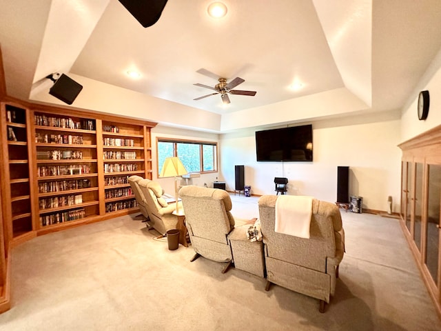 carpeted living room featuring ceiling fan and a tray ceiling