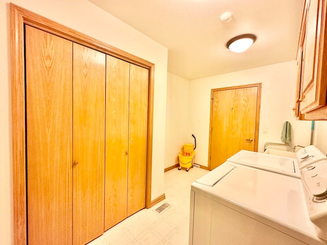 washroom with washing machine and clothes dryer and cabinets